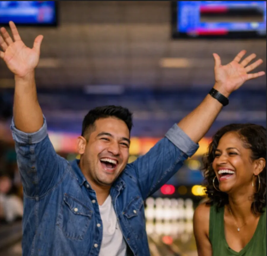 Two friends celebrating and laughing at a bowling alley